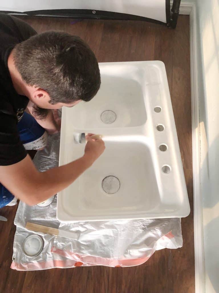 man painting kitchen sink