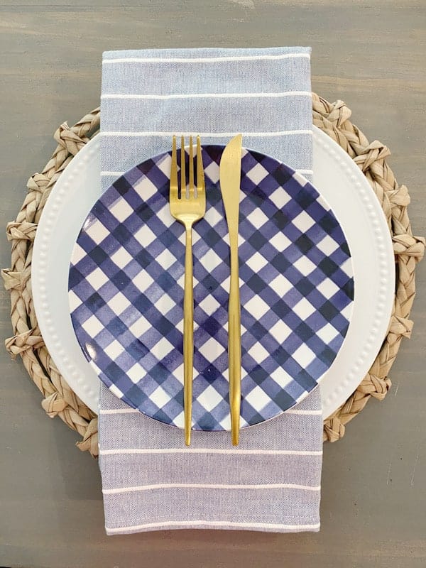 table setting with blue check plates and gold flatware