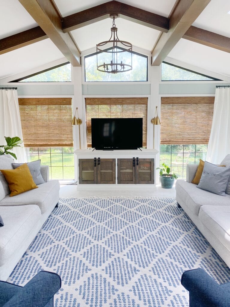 living room with white trim featuring a blue and white area rug and cream colored sofas with throw pillows