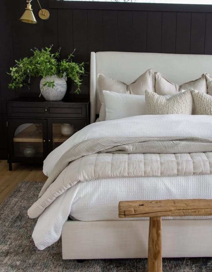 Neutral layered bedding against black vertical shiplap wall by Jennifer Neathery